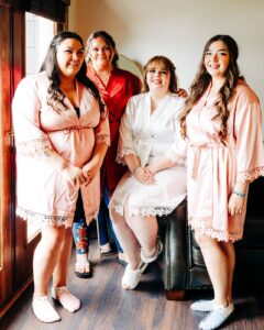 Portrait of bride with bridesmaids wearing satin robes in Casino Suite at Kwataqnuk Resort