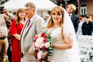 Bride walking with father down aisle during wedding ceremony