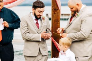 Best man handing rings to groom during wedding ceremony on Flathead Lake