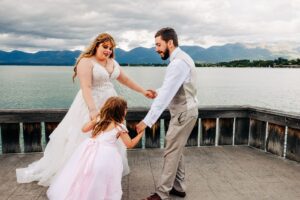 Bride and groom dancing with daughter on dock at Kwataqnuk Resort in Polson, MT