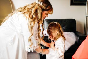 Bride helping her young daughter get dressed for wedding in Western Montana