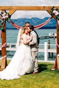 Bride and groom kissing during wedding ceremony on shore of Flathead Lake