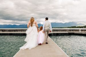 Bride and groom holding daughters hands and walking on dock at Kwataqnuk Resort