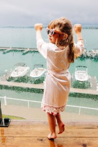 Flower girl in pink satin robe and heart sunglasses on balcony at Kwataqnuk Resort