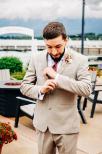 Groom adjusting cufflinks outdoors at Kwataqnuk Resort