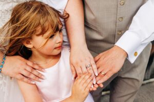 Bride, groom, and daughter hands showing wedding rings