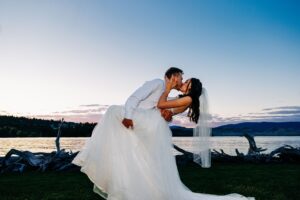 Bride and groom dip and kiss at dusk at Flathead Lake Forevers