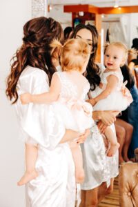 Bride holding her baby daughter looking in mirror at Flathead Lake Forevers