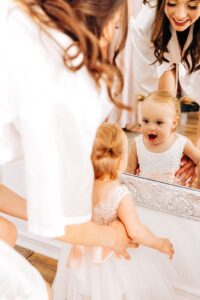 Bride and her baby daughter smiling at themselves in the mirror at Flathead Lake Forevers