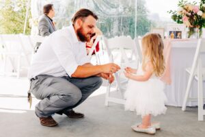 Wedding guest helping little girl with bubbles at wedding reception