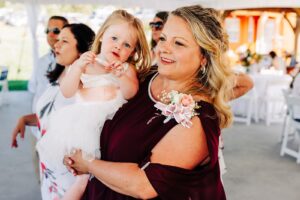 Mother of groom holding little girl at Flathead Lake Forevers wedding reception