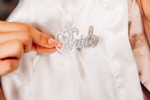 Close up of rhinestone bride pin on white satin robe