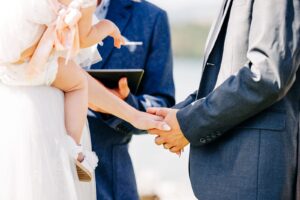 Close up of bride and groom holding hands during wedding ceremony at Flathead Lake Forevers in Big Arm, MT