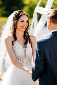 Bride smiling at husband during wedding ceremony at Flathead Lake Forevers