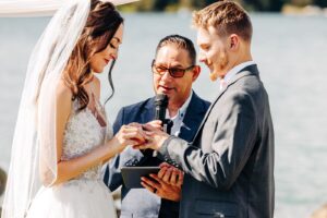 Bride and groom exchanging rings during wedding ceremony at Flathead Lake Forevers