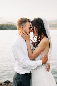 Bride and groom embracing at Flathead Lake Forevers with Flathead Lake in background