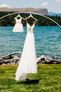 Hanging bride and flower girl dresses outdoors on shore of Flathead Lake at Flathead Lake Forevers