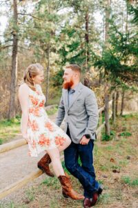 Missoula engaged couple sitting on wood fence in forest
