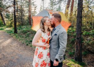 Engagement picture Missoula couple kissing under umbrella at Lincolnwood Trailhead