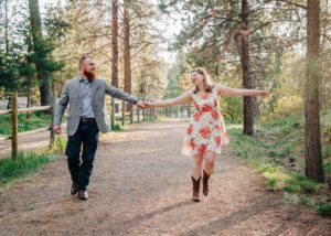 Engaged couple walking and laughing in the forest together