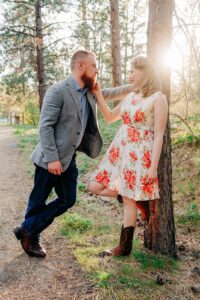 Missoula engaged couple posing against forest tree at Lincolnwood Trailhead