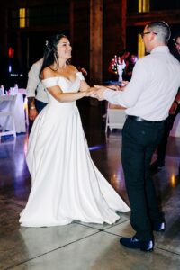 Bride dancing with her brother during nighttime indoor wedding reception party at Snowline Acres