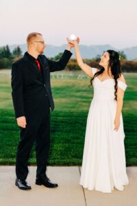 Bride and groom with hands raised together as if holding the harvest supermoon at Snowline Acres in Kalispell, MT