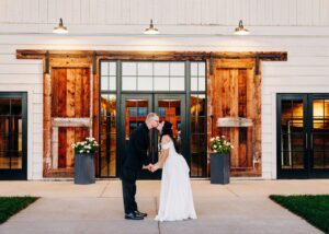 Bride and groom kissing outside at dusk in front of the Ashley Creek Historic Venue in Kalispell, MT