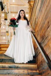 Bride holding bouquet walking down wood stairs at Ashley Creek Historic Venue in Kalispell, MT