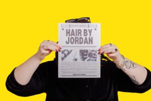 Brand image Missoula hair stylist holding flyer on yellow backdrop