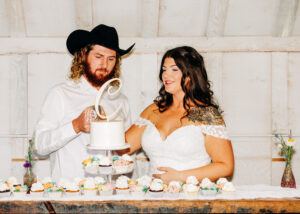 Bride and groom cutting cake inside white barn at McVey Homestead