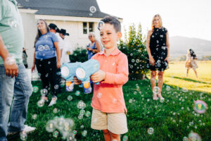 Little boy playing with bubble blowers on lawn at McVey Homestead wedding venue