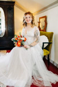 Portrait of bride sitting in green velvet chair in the farmhouse at McVey Homestead