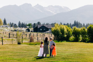 Wedding guests standing on lawn at McVey Homestead with Bitterroot Mountains in background