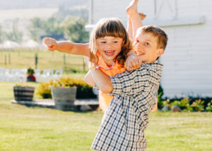 Kids playing airplane on lawn at McVey Homestead wedding reception in Victor, Montana
