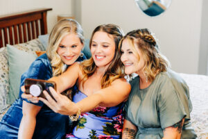 Three girls sitting on bed taking selfie in farmhouse at McVey Homestead