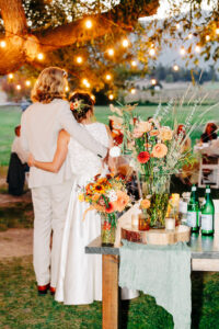 Bride and groom embracing under string lights at evening wedding reception in Victor-Montana
