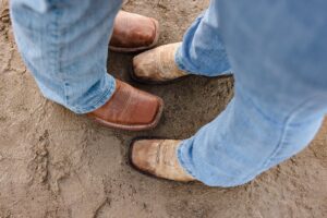 Close-up of engaged couple's brown cowboy boots and jeans