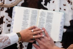 Close-up of engaged couple's hands resting on top of an open-face Bible