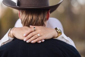 Close-up of woman's hands with engagement ring clasps around her fiance's neck