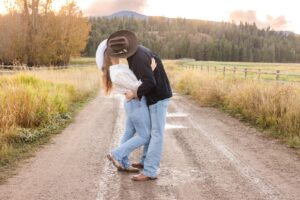 Montana couple kissing on dirt road at sunset with cowboy hats at Lazy Sousa Ranch in Huson, MT