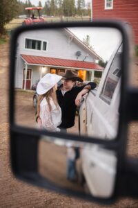 Engaged couple standing close and looking at each other as photographed through truck's rear view mirror
