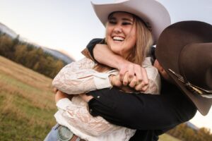 Engaged couple hugging and smiling wearing cowboy hats at Lazy Sousa Ranch in Huson, MT