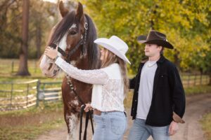 Engaged couple petting Clydesdale horse at Lazy Sousa Ranch in Huson, MT