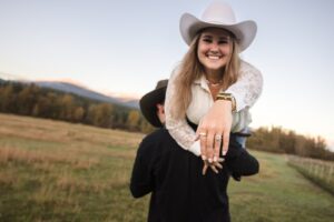 Woman carried on man's shoulder showing off her engagement ring